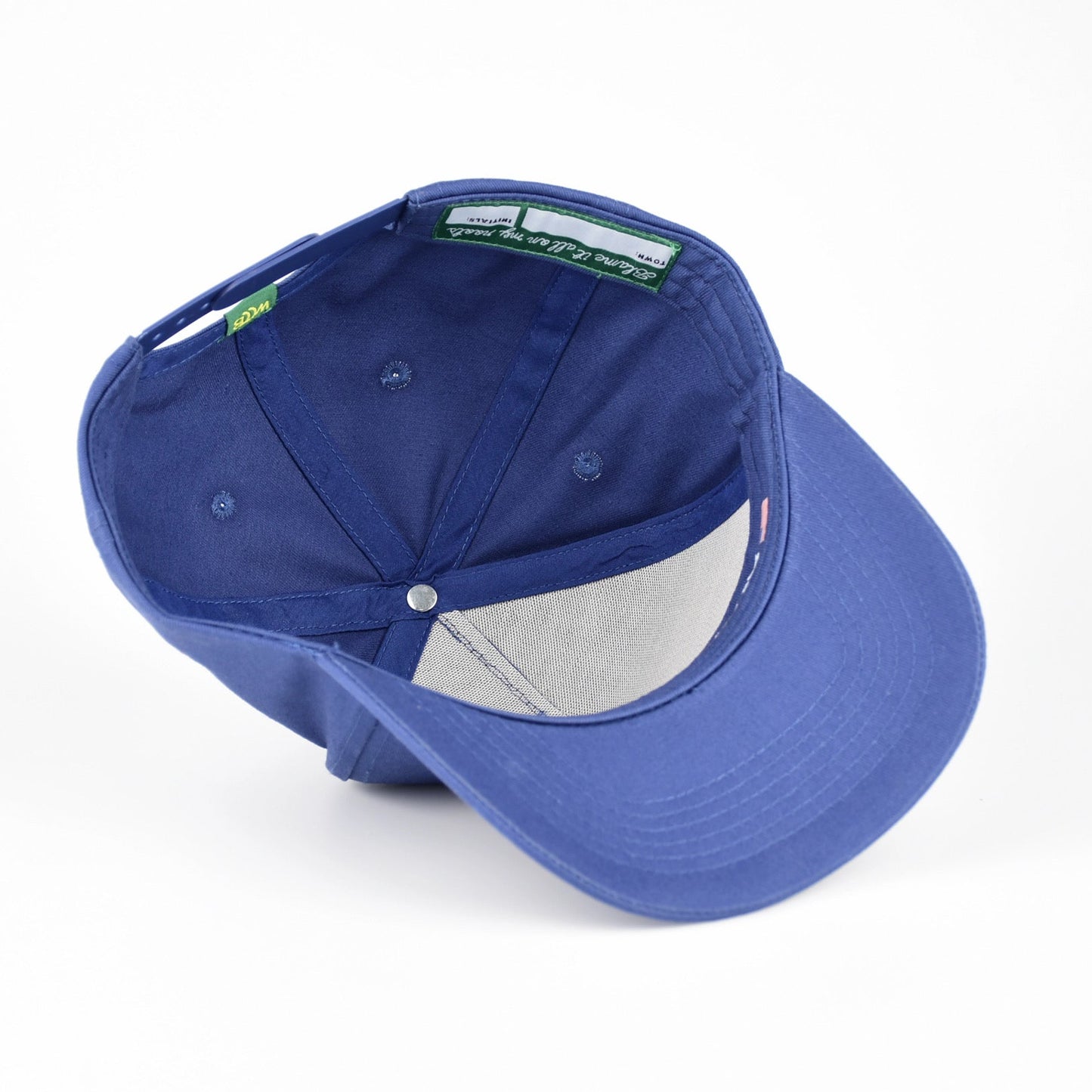 A royal blue baseball cap shown from a three-quarters rear angle, featuring a structured blue crown, a curved brim, and a light gray mesh back panel, photographed on a seamless white background.