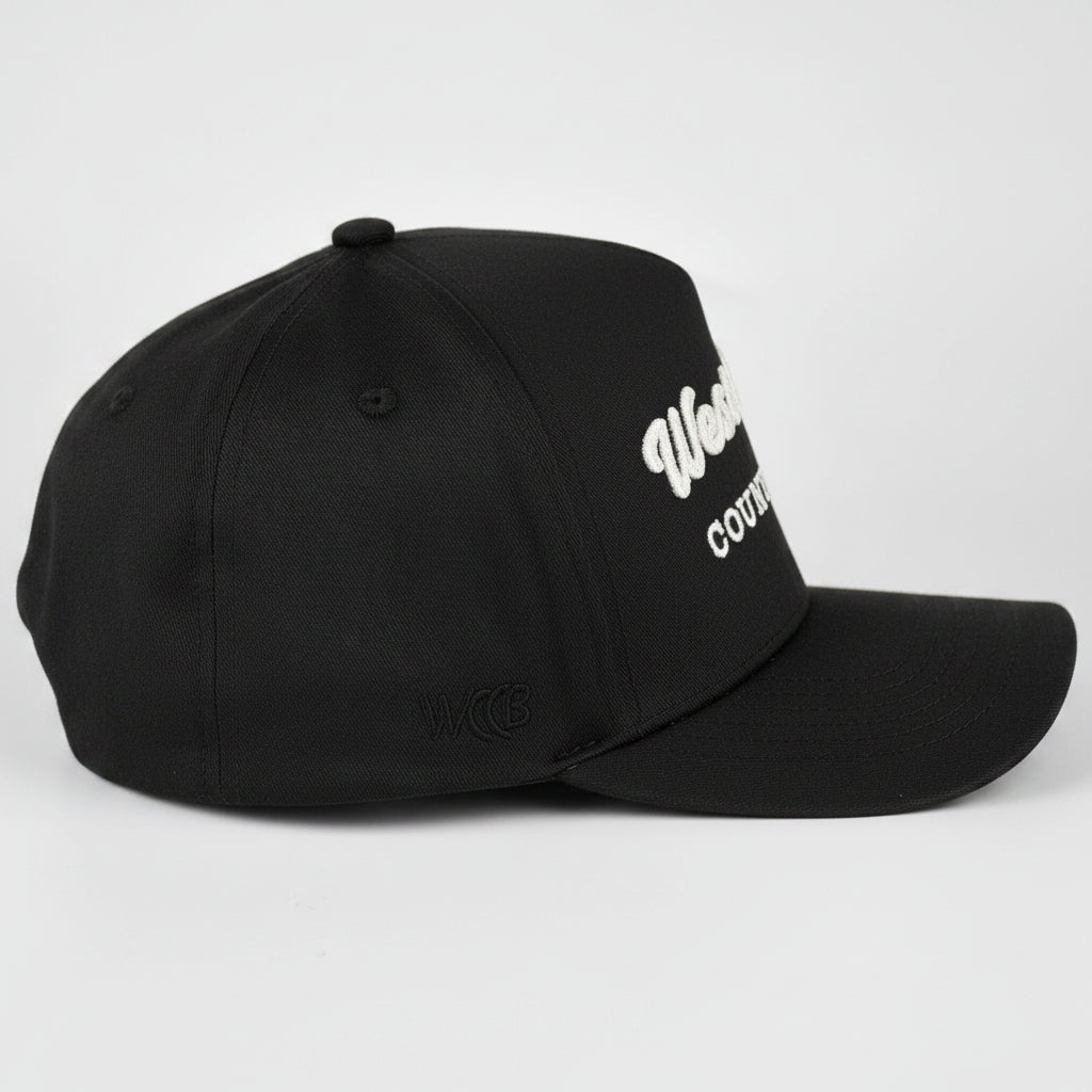 A black baseball cap with WCCB embroidered text on the side, photographed on a light gray studio background.