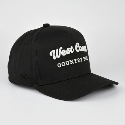 A Black baseball cap with 'West Coast COUNTRY BOY' embroidered in white on the front, shown on a light gray studio background.