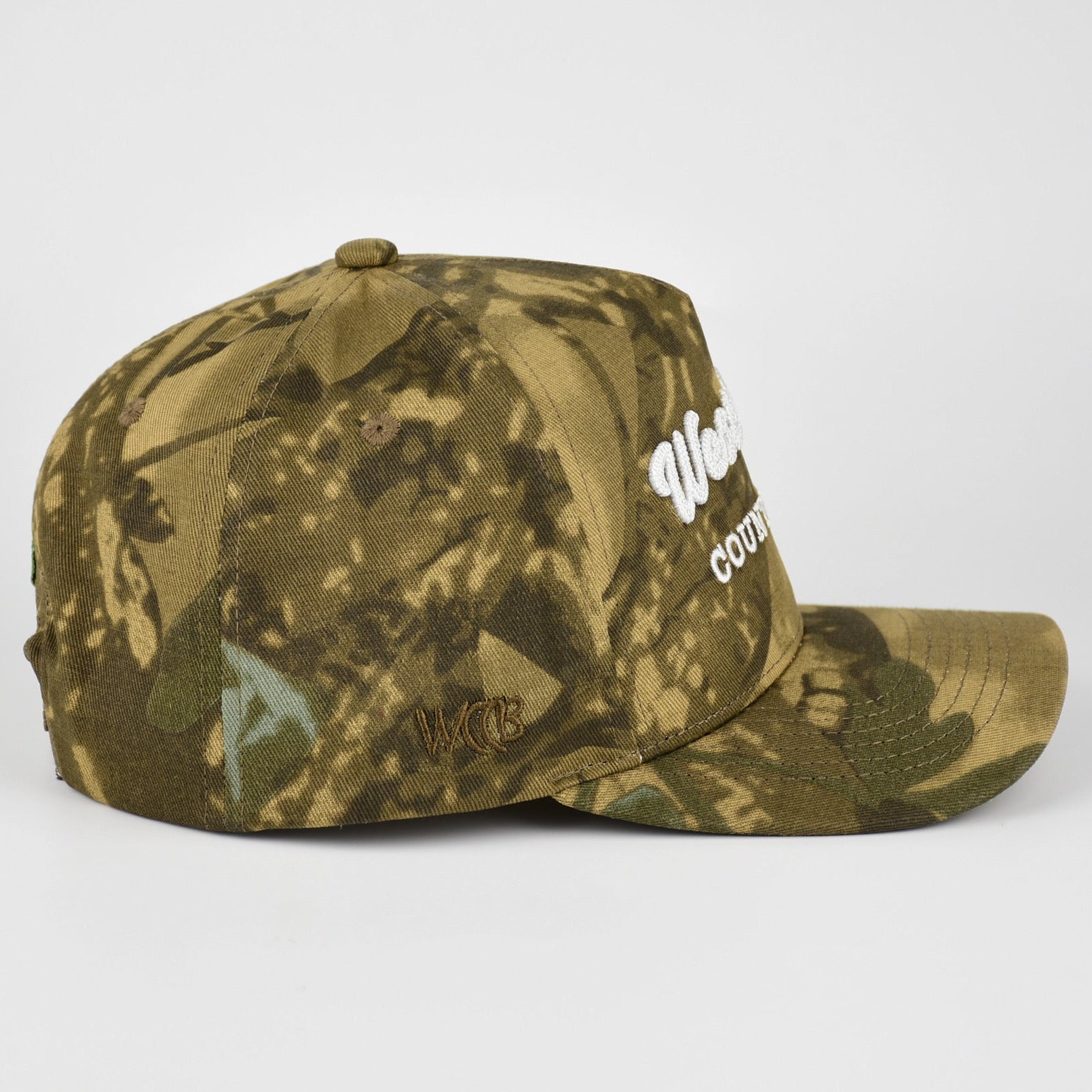A camouflage baseball cap with a WCCB embroidered logo on the side, photographed against a plain light gray background.