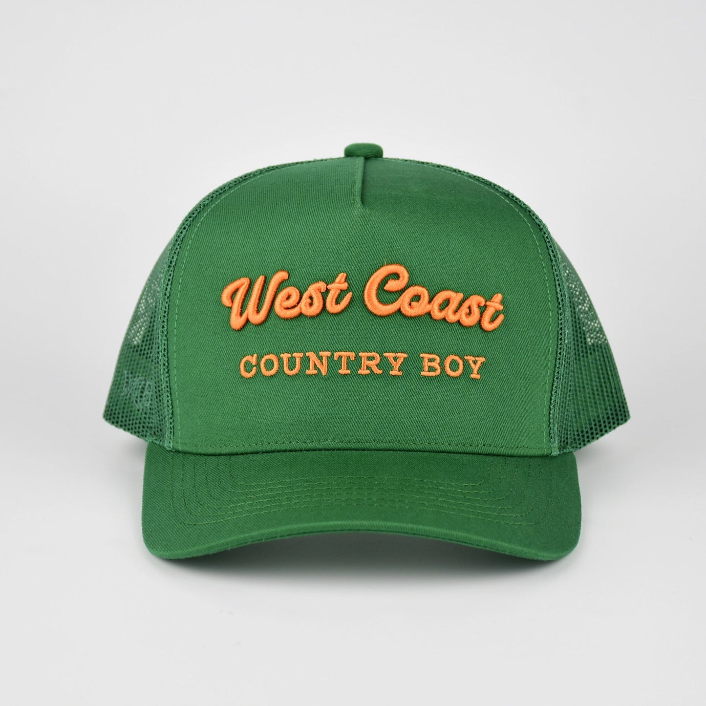 A green trucker-style cap with orange embroidered text reading 'West Coast COUNTRY BOY' on the front, shown against a light gray studio background.