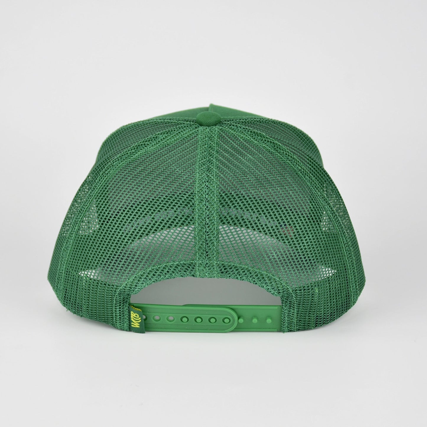A green mesh-back trucker cap shown from the back, featuring a green fabric back and an adjustable snap closure, photographed against a light gray studio background.