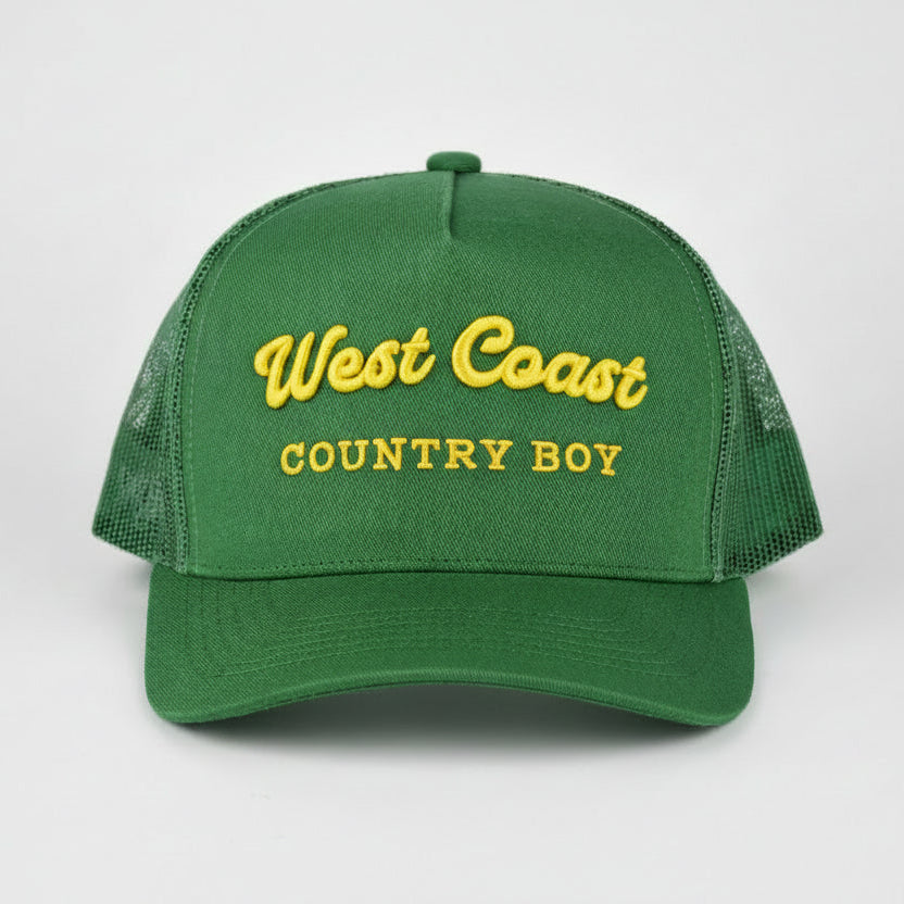 A green trucker-style cap with yellow embroidered text reading 'West Coast COUNTRY BOY' on the front, shown against a light gray studio background.