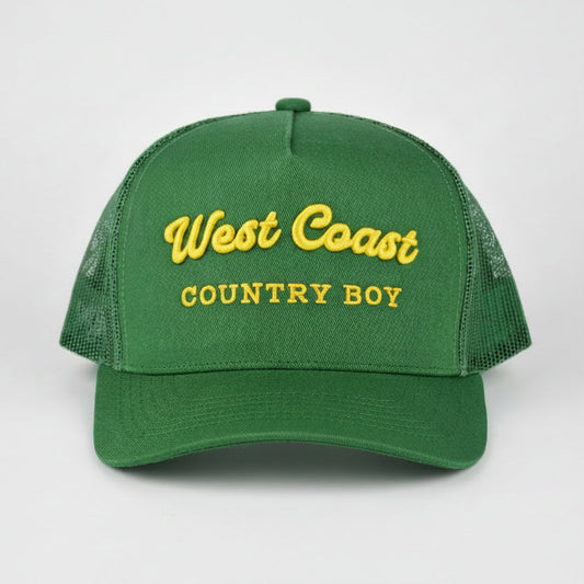 A green trucker-style cap with yellow embroidered text reading 'West Coast COUNTRY BOY' on the front, shown against a light gray studio background.