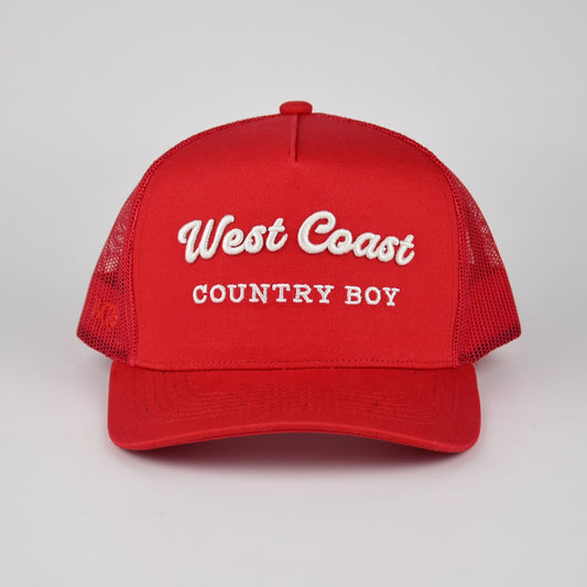 A red trucker-style cap with white embroidered text reading 'West Coast COUNTRY BOY' on the front, shown against a light gray studio background.