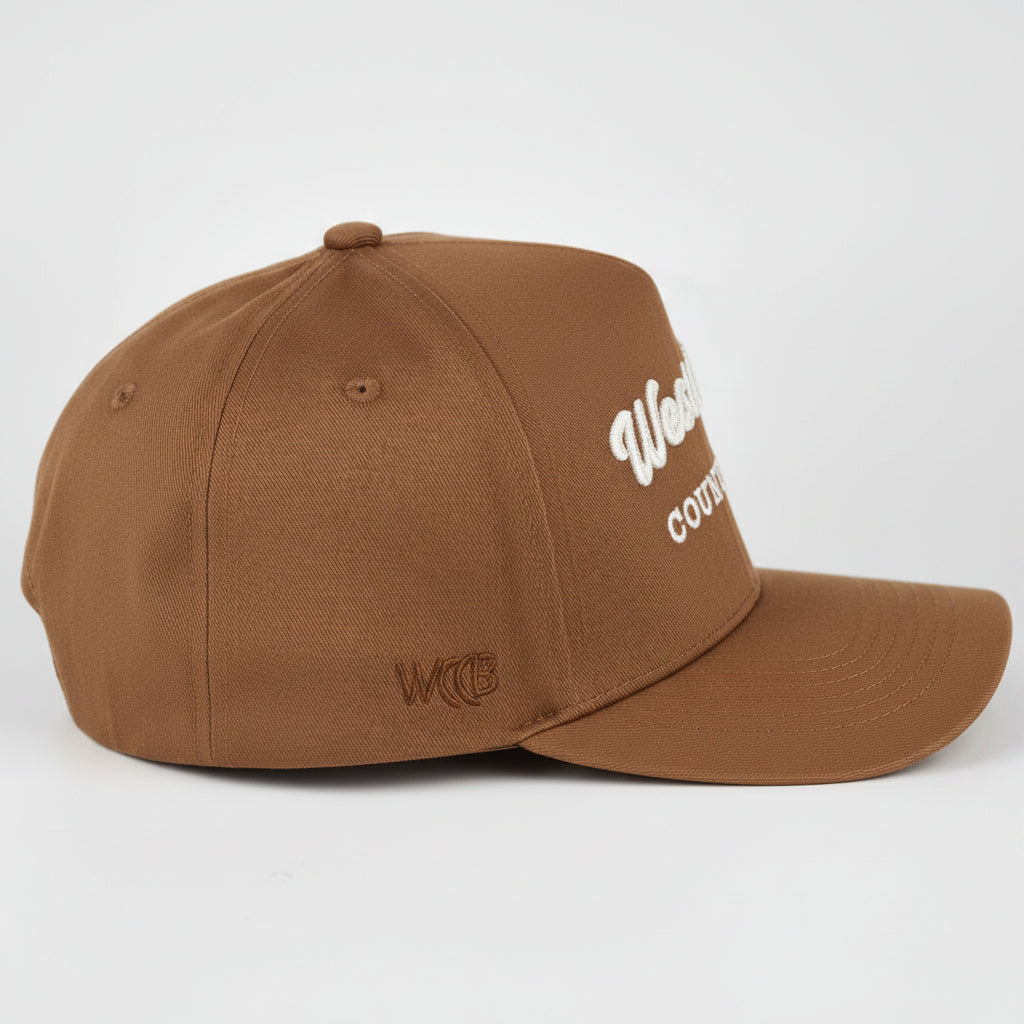A royal blue baseball cap with white embroidered WCCB text on the side, photographed on a light gray studio background.